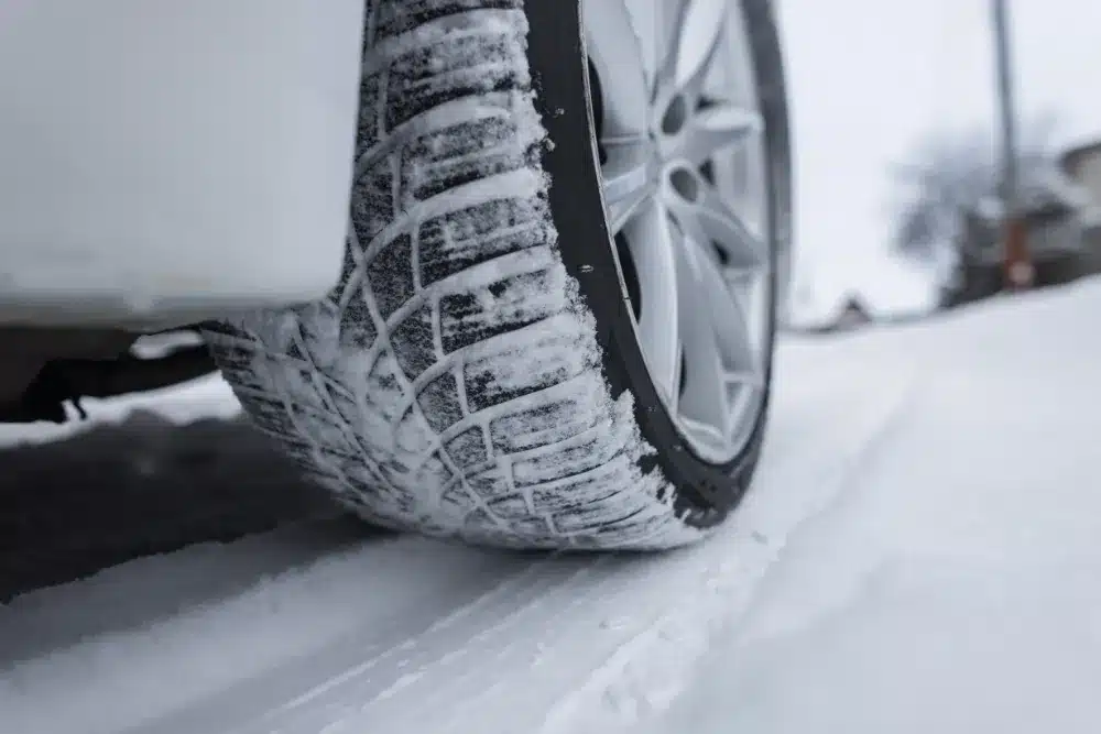 Winter tires, auto repair in Jackson, MO by Charlie’s Tire and Automotive. Image of a close-up snow-covered tire with deep tread gripping an icy road, highlighting the importance of proper tires for safe winter traction, braking, and cold-weather driving performance.