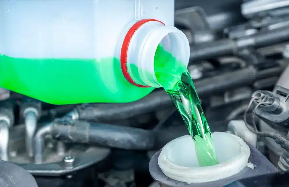 Pouring green fluid into engine reservoir