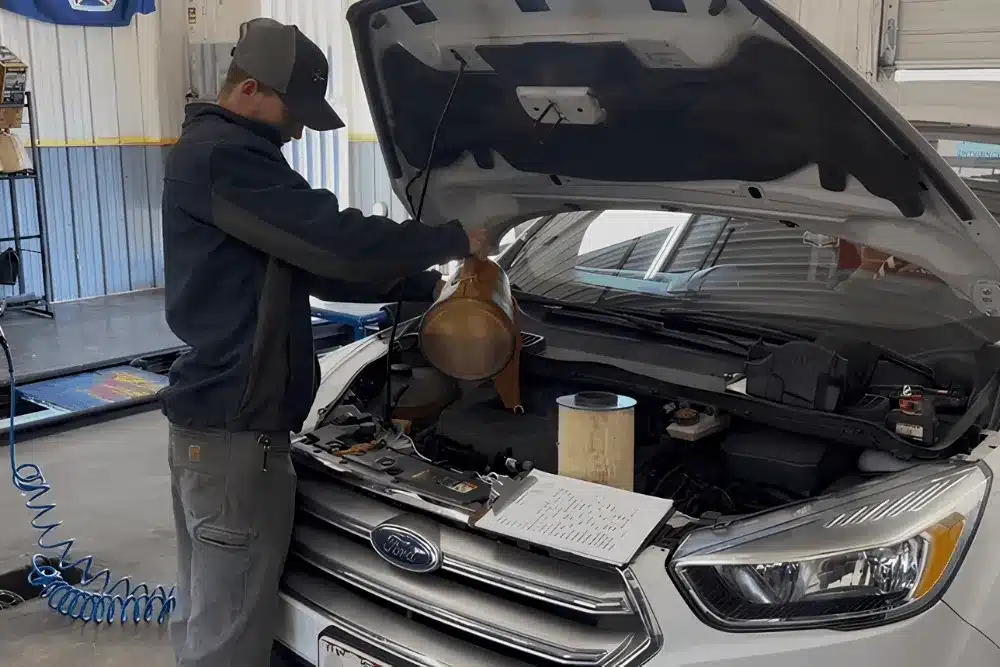 Lube services in Jackson, MO, at Charlie's Tire and Automotive. Image of a technician pouring fresh engine oil into a Ford SUV during a professional oil change service to help maintain engine performance and reliability.