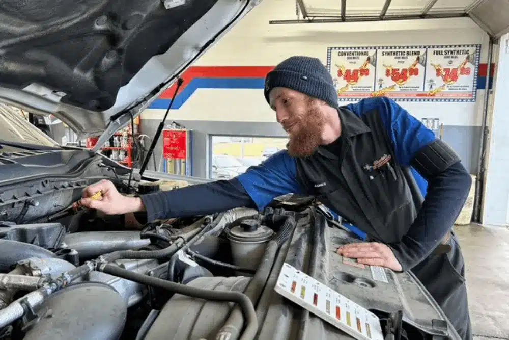 Vehicle checklist, auto repair in Ste. Genevieve, MO, at Charlie's Tire and Automotive. Image of an automotive technician checking the engine oil level with a dipstick during a routine oil change and vehicle maintenance service to ensure proper engine protection.