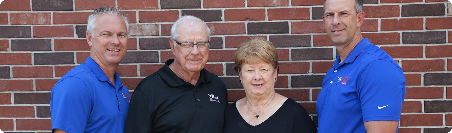 Auto Repair In MO & IL At Charlie’s Tire and Fast Lube. Four people posing against brick wall
