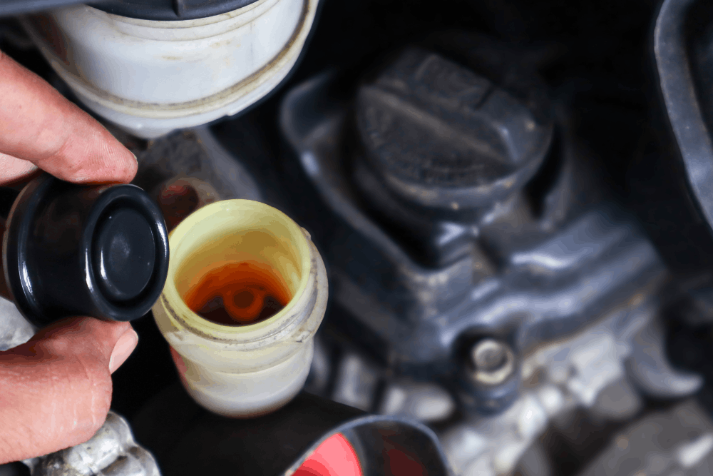 Brake fluid moisture, auto repair in Sparta, IL at Charlie’s Tire and Automotive. Image of a technician checking fluid inside a brake fluid reservoir to support safe, reliable braking performance.