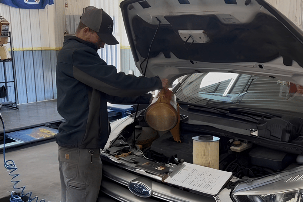 Oil Change in Ste. Genevieve, MO At Charlie's Tire and Automotive. Image of auto technician pouring oil into an engine bay during an oil change service